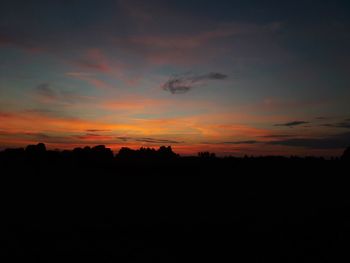 Silhouette landscape against dramatic sky during sunset