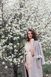 Portrait of beautiful woman standing by flower tree