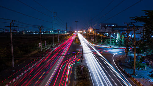 Light trails on road in city against sky at night