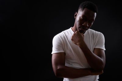 Young man looking away against black background