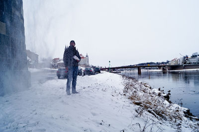 Young man standing on snow by river