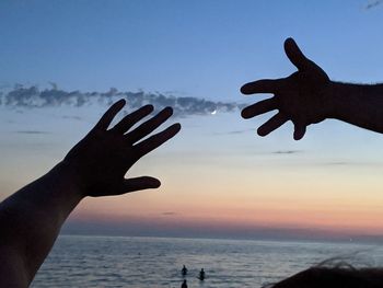Silhouette people on beach against sky during sunset