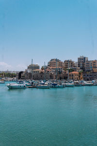 Buildings by sea against clear sky in heraklion port