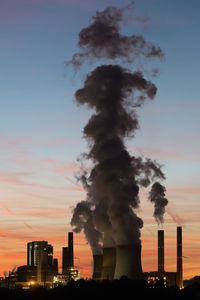 Smoke emitting from factory against sky during sunset