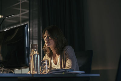 Woman looking away while sitting on table