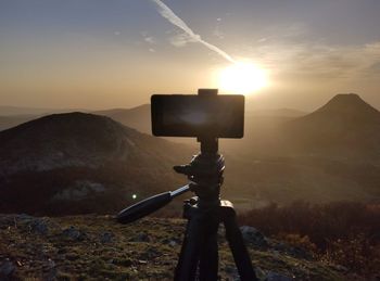 Low angle view of security camera on mountain against sky during sunset