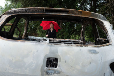 People in abandoned car by trees during rainy season