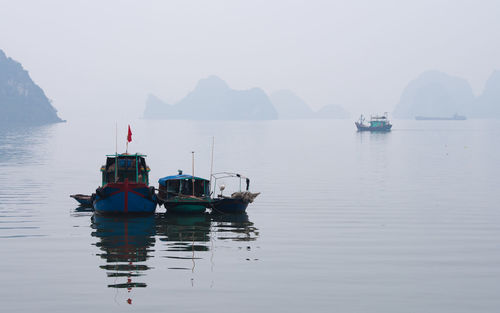 Fishing boats in sea against sky