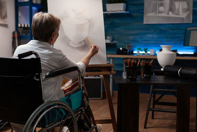 Rear view of woman drawing on canvas at home