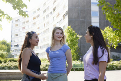 Smiling young female friends standing and talking together