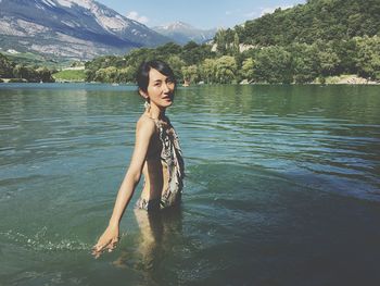 Portrait of woman standing in lake against mountains