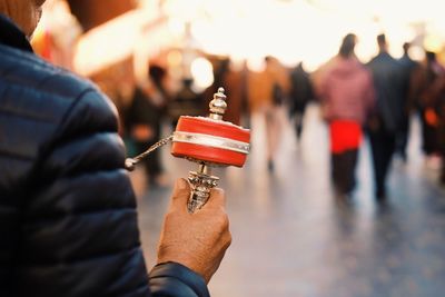 Close-up of man holding prayer wheel while standing outdoors