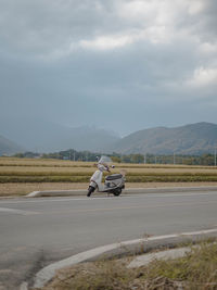 Man riding motorcycle on road against sky