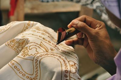 Cropped hand of artisan making design on textile