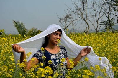 Young woman with yellow flowers in field