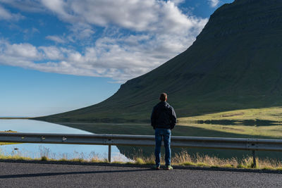 Rear view of man standing on road against mountain