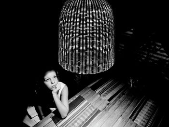 High angle view of girl looking at illuminated pendant light in darkroom