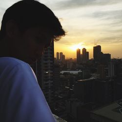 Midsection of man in city against sky during sunset