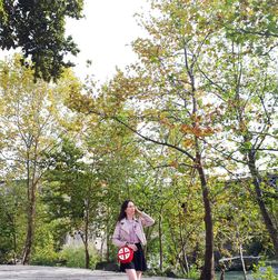 Woman standing by trees against plants
