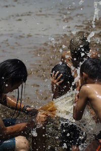 Man splashing water on children at riverbank
