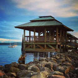 Built structure on rocks by sea against sky