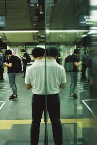 Rear view of people walking on illuminated street in city at night