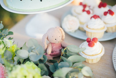 Little plush rabbit toy among raspberry cupcakes celebration birthday