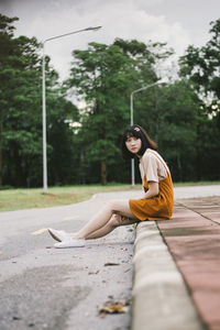 Side view of young woman sitting on road