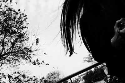 Woman standing by tree against sky