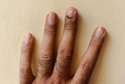 Cropped hand of person gesturing against wall