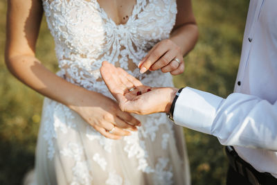 Midsection of bride giving berries on grooms hand