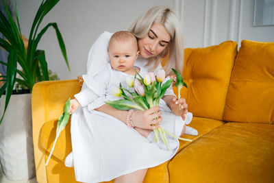 Portrait of cute baby girl sitting on sofa at home