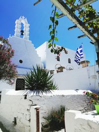 Low angle view of flags on building by tree against sky