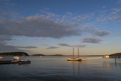 Sailboats sailing on sea against sky during sunset