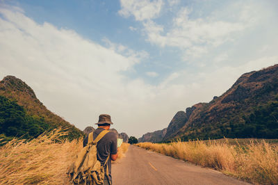 Rear view of man riding motorcycle on road against sky