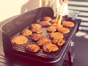 Cropped hand of person preparing meat on barbecue grill