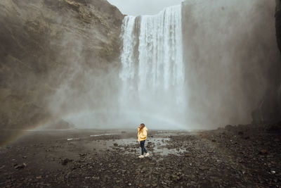 Rear view of man standing against waterfall