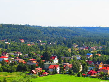 Trees and houses on field by buildings against sky