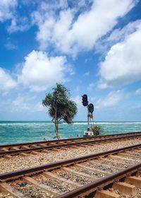 Railroad tracks by sea against sky