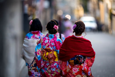 Rear view of women wearing kimono while walking on street in city