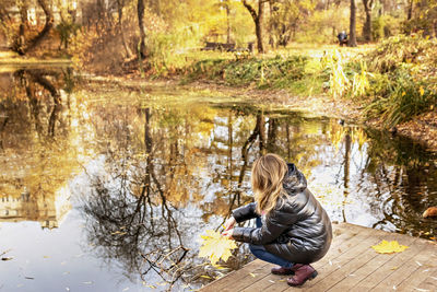 A young woman on the shore of a pond in an autumn park.