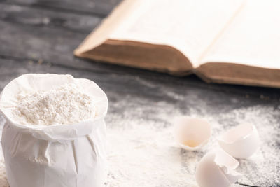 Close-up of flour by cracked eggshells on table