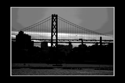 Silhouette of suspension bridge against sky