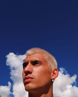Low angle portrait of man looking away against sky