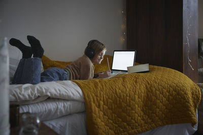 Low section of woman relaxing on bed at home