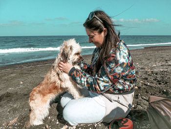 Woman with dog sitting on beach