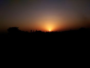 Silhouette landscape against clear sky at sunset