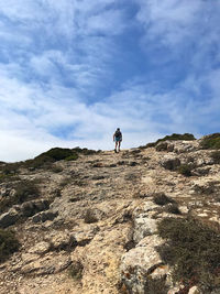 Low angle view of men on rock against sky