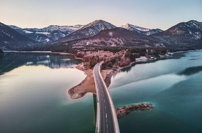 Bridge over lake and mountains against sky