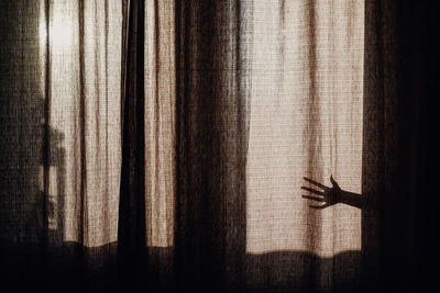 Shadow of person hand on curtain at home